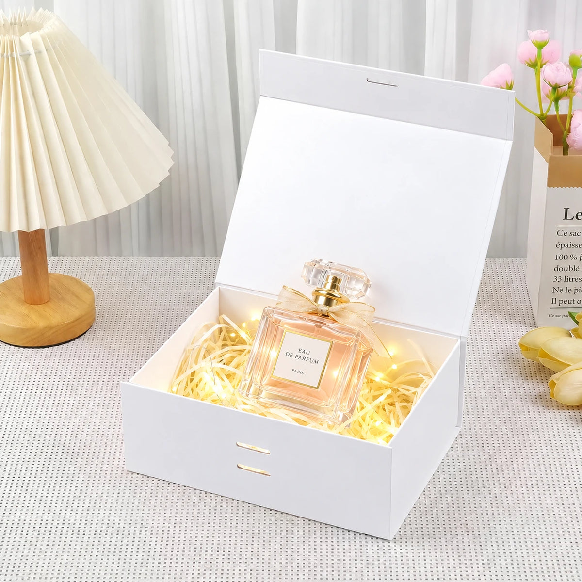 Illustrative perfume gift styling in an open white ribbon gift box; perfume and props not included.